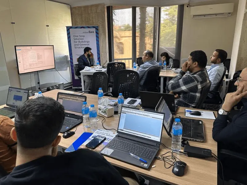 Engineers at laptops following the MIDAS Gen workshop, with a midas Gen banner at the front