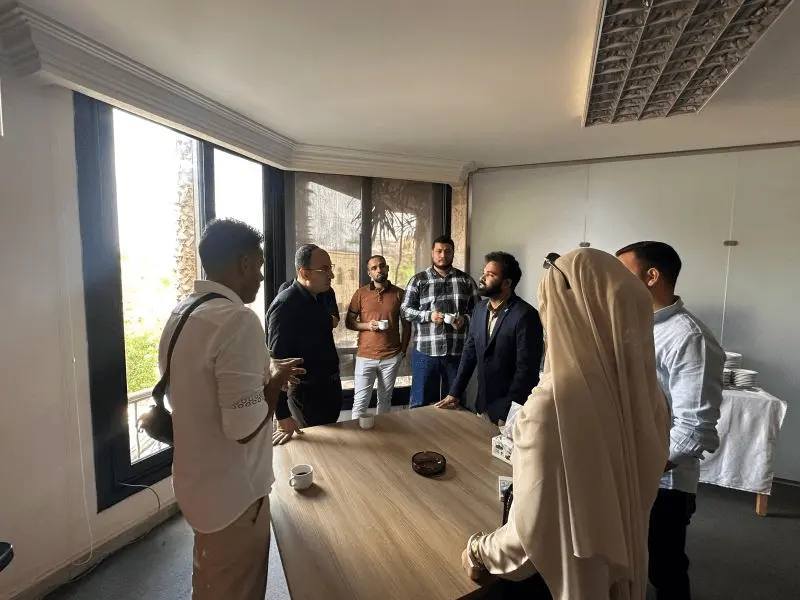 Participants and the MIDAS trainer talking over coffee